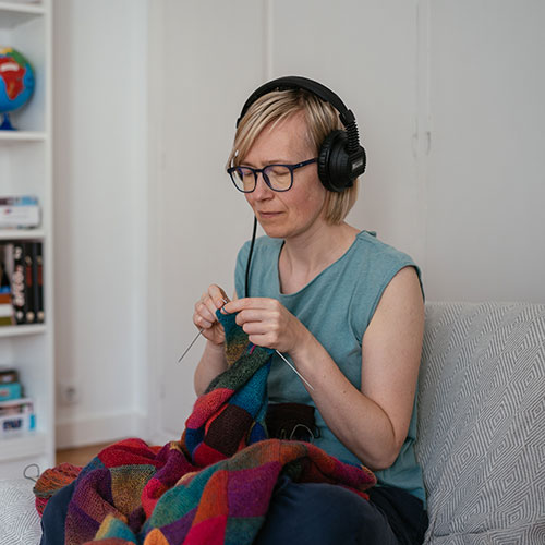 girl wearing glass and a Tomatis device's earphones sitting and knitting