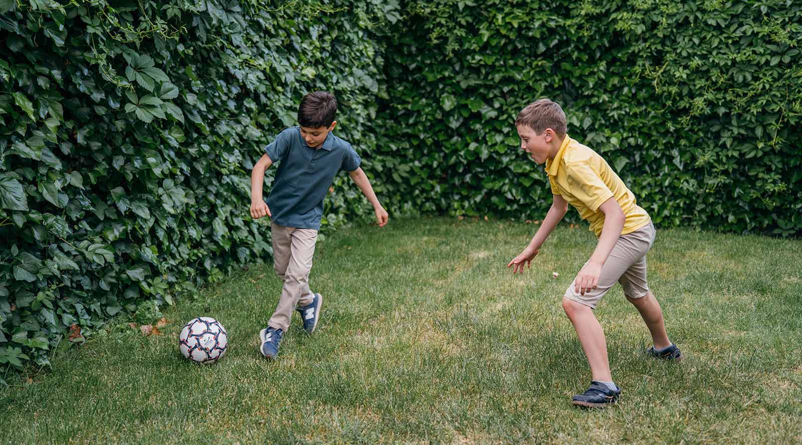 two boys playing football on the grass