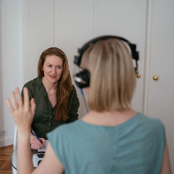 the therapist doing a listening test to the blond girl with the headphones and left hand raised
