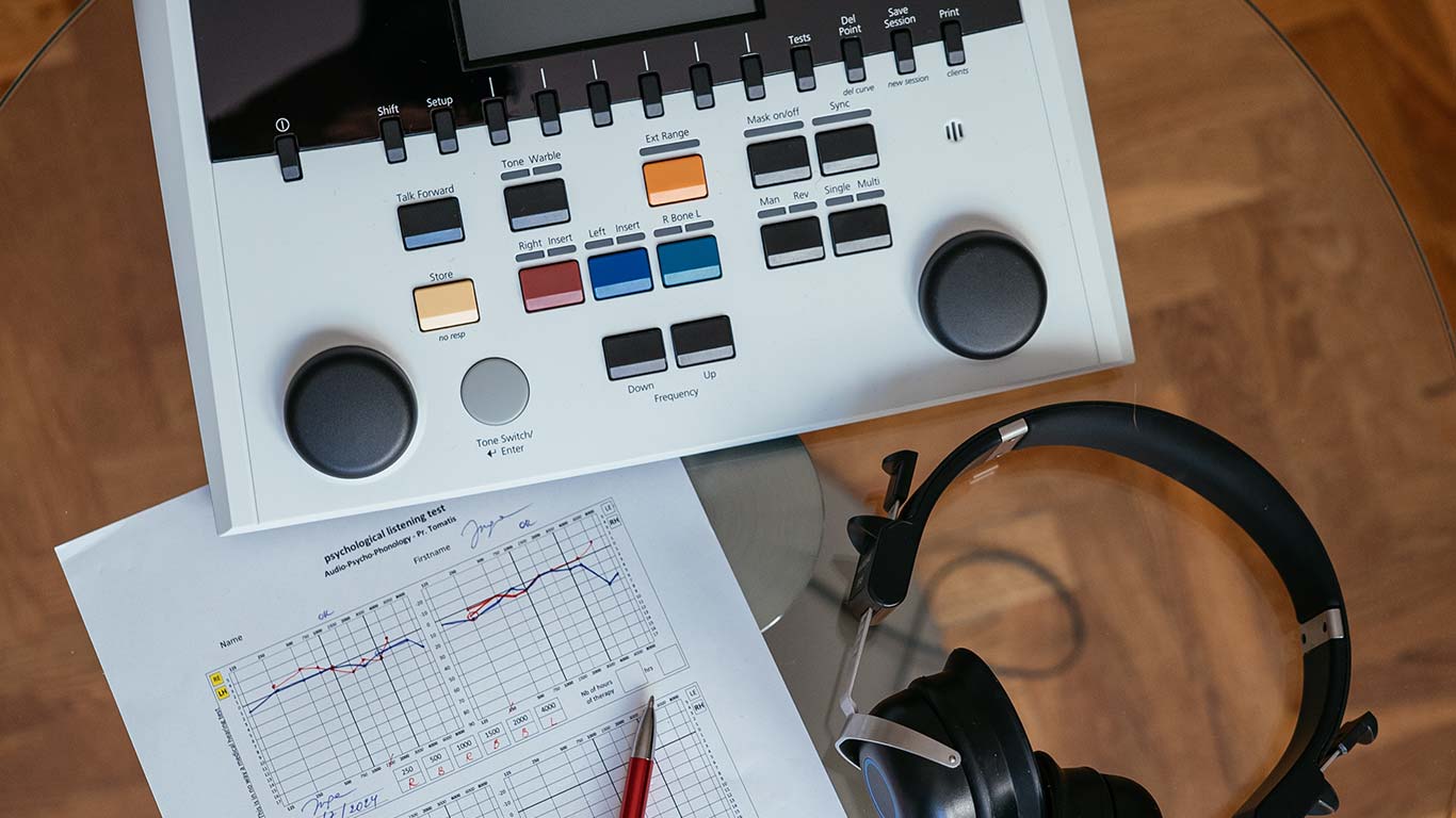 Tomatis therapy device with control panel and headphones placed on a table, next to a printed psychological listening test chart